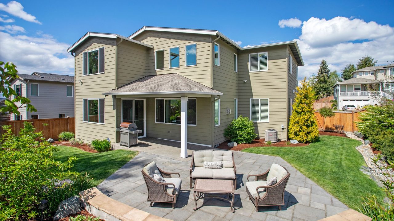 A finished rear yard — paver patio and seating, boulder edging, planting beds, cut lawn and fencing