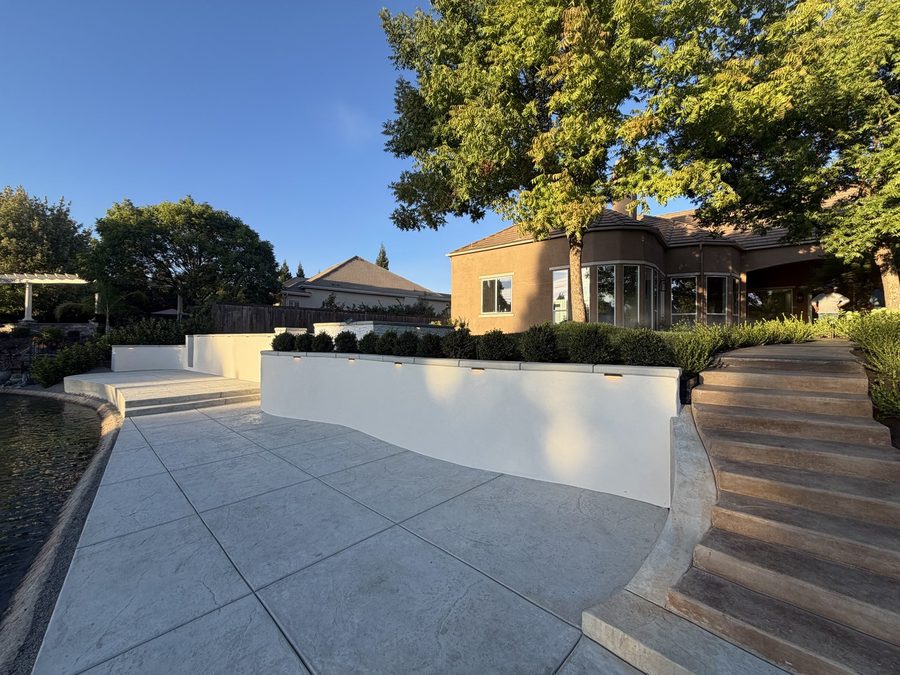 Curved white seat walls, stamped concrete terracing and stone steps rising to the house