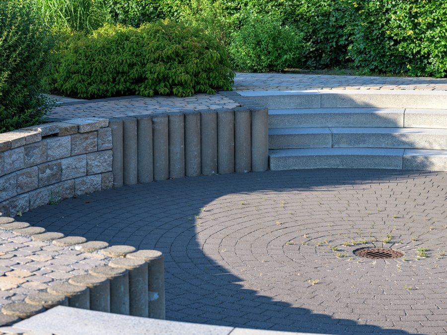 A curved paver terrace stepping up to a block retaining wall and planting