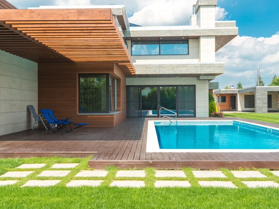 A pool deck with stepping stones set into lawn beside a covered terrace